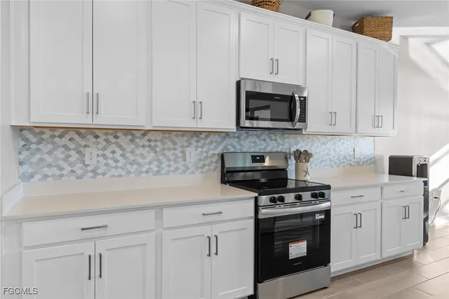 a kitchen with white cabinets and black appliances