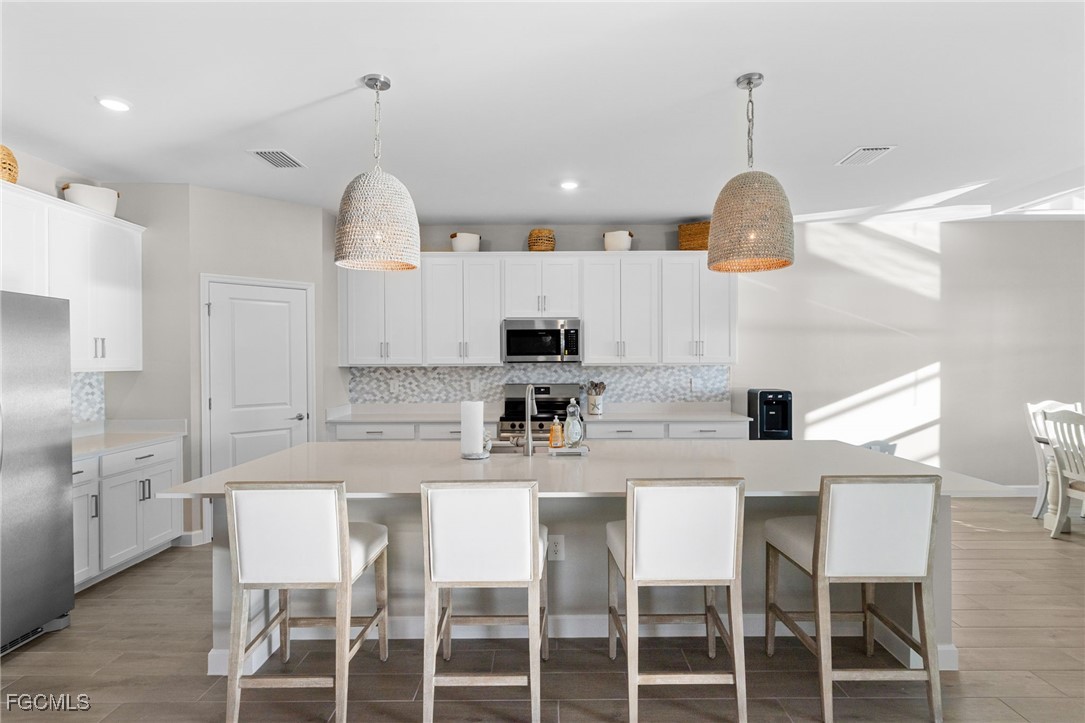 10575 Timber Creek Drive Fort Myers, FL 33913 - Photo 20 of 50 a kitchen with kitchen island a dining table and a wooden floor