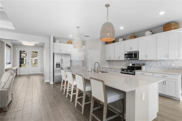 a kitchen with stainless steel appliances kitchen island granite countertop a sink a stove a refrigerator cabinets and chairs