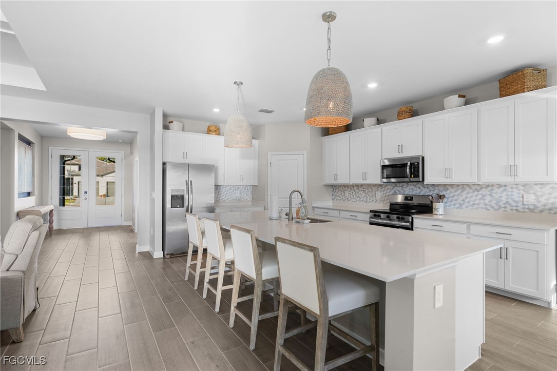 10575 Timber Creek Drive Fort Myers, FL 33913 - Photo 10 of 50 a kitchen with stainless steel appliances kitchen island granite countertop a sink a stove a refrigerator cabinets and chairs
