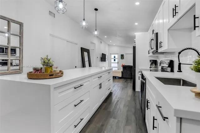 a kitchen with stainless steel appliances granite countertop a stove a refrigerator a dining table and chairs with wooden floor