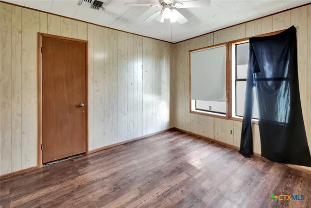 an empty room with wooden floor cabinet and windows