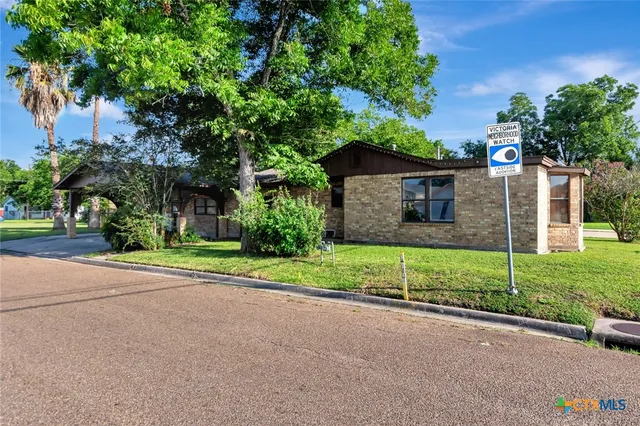 a view of a house with a yard and large tree