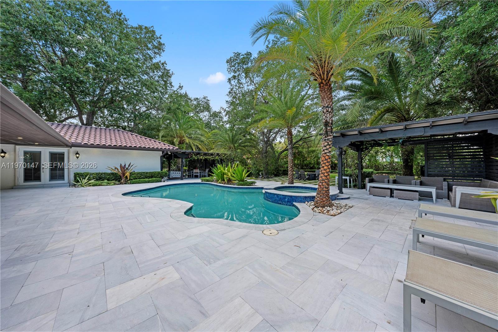 8801 Southwest 124th Street Miami, FL 33176 - Photo 34 of 48 a view of patio with table and chairs under an umbrella with large trees