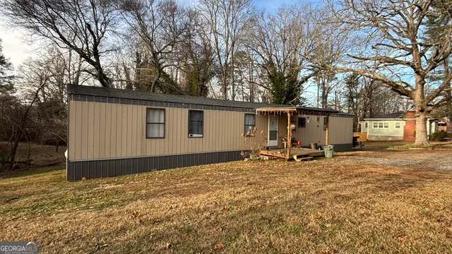 a backyard of a house with table and chairs and a large tree