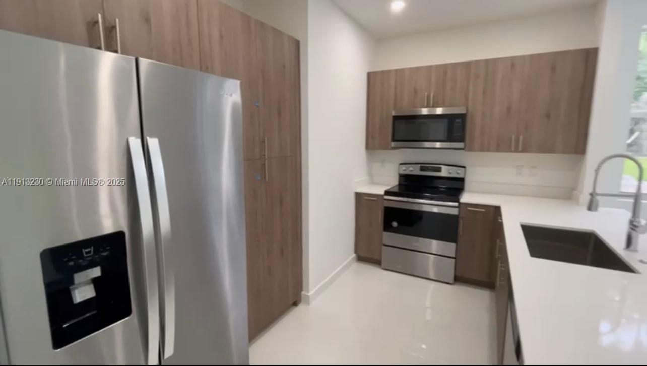 1350 Crystal Way, Unit 101 Delray Beach, FL 33444 - Photo 10 of 13 a kitchen with stainless steel appliances a refrigerator a stove a microwave and sink