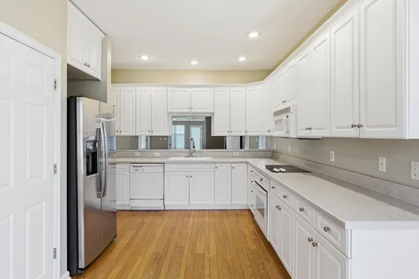 a kitchen with granite countertop white cabinets and white appliances with wooden floor