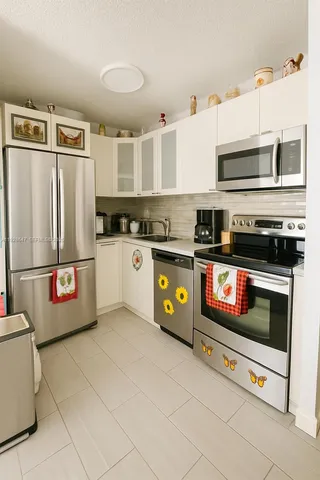 a kitchen with stainless steel appliances granite countertop a refrigerator a stove a sink and a microwave