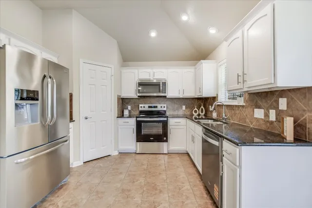 a kitchen with stainless steel appliances granite countertop a refrigerator stove and sink