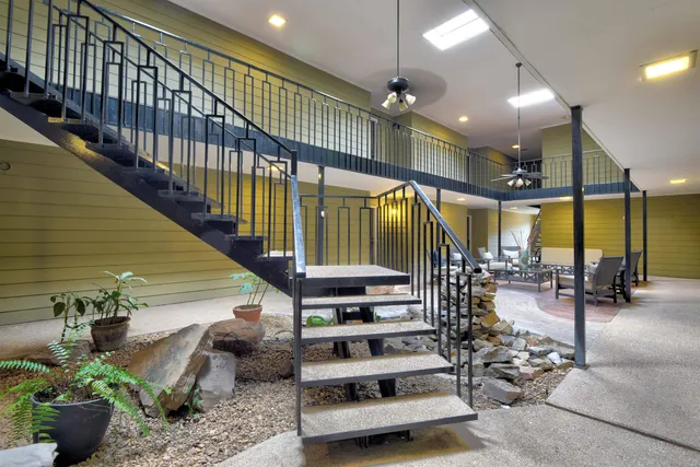 a room with lots of potted plants and large windows