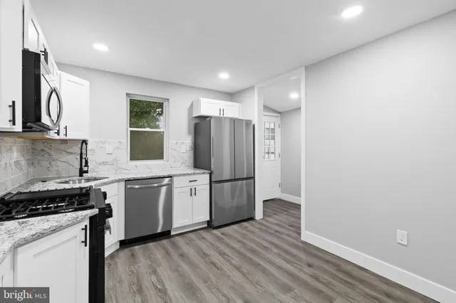 a kitchen with stainless steel appliances granite countertop a refrigerator a sink dishwasher and wooden cabinets with wooden floor