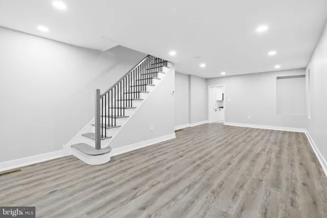 a view of an empty room with wooden floor and stairs