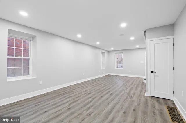an empty room with wooden floor and windows