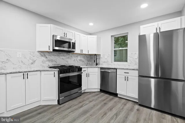 a kitchen with granite countertop a refrigerator stove and microwave