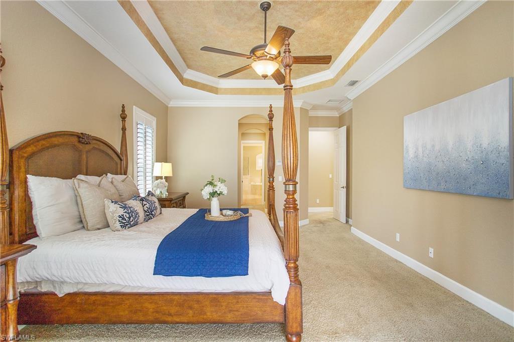 9807 Nickel Ridge Circle Naples, FL 34120 - Photo 13 of 50 a bedroom with a large bed and a chandelier