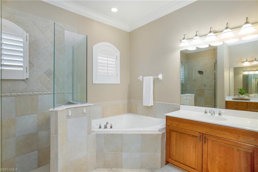 9807 Nickel Ridge Circle Naples, FL 34120 - Photo 15 of 50 a bathroom with a tub a double vanity sink and a mirror