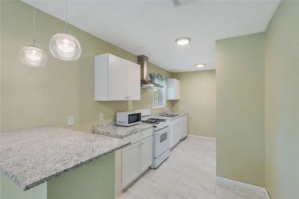 a kitchen with granite countertop stainless steel appliances a stove and a microwave