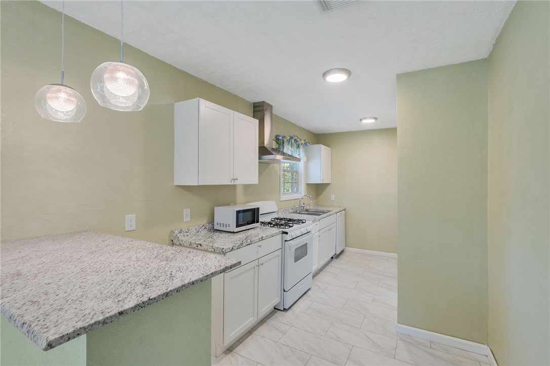 401 East 3rd Street Hearne, TX 77859 - Photo 19 of 25 a kitchen with granite countertop cabinets a stove a sink and a island with wooden floor