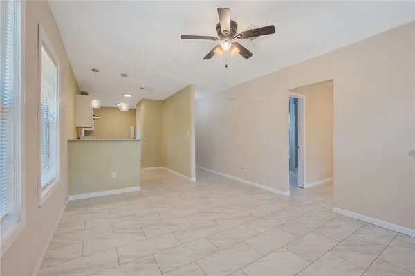 a view of a livingroom with a ceiling fan & kitchen space