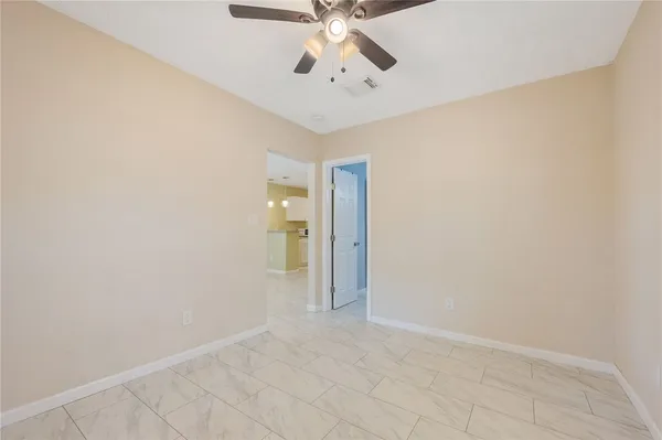 an empty room with chandelier fan and windows