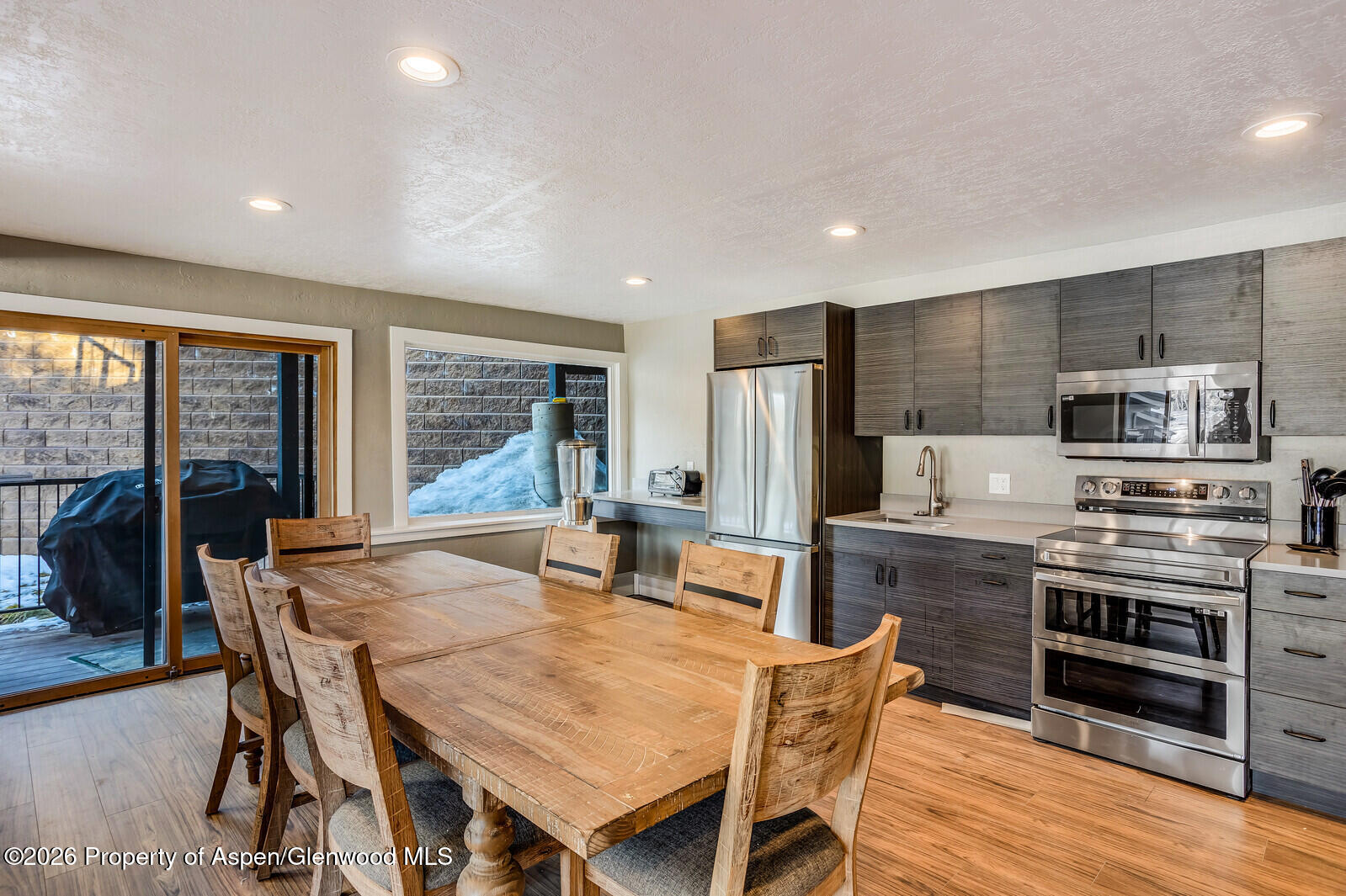 55 Upper Woodbridge Road, Unit E2 Snowmass Village, CO 81615 - Photo 32 of 41 a kitchen with stainless steel appliances granite countertop a stove a refrigerator a kitchen island a table and chairs in it