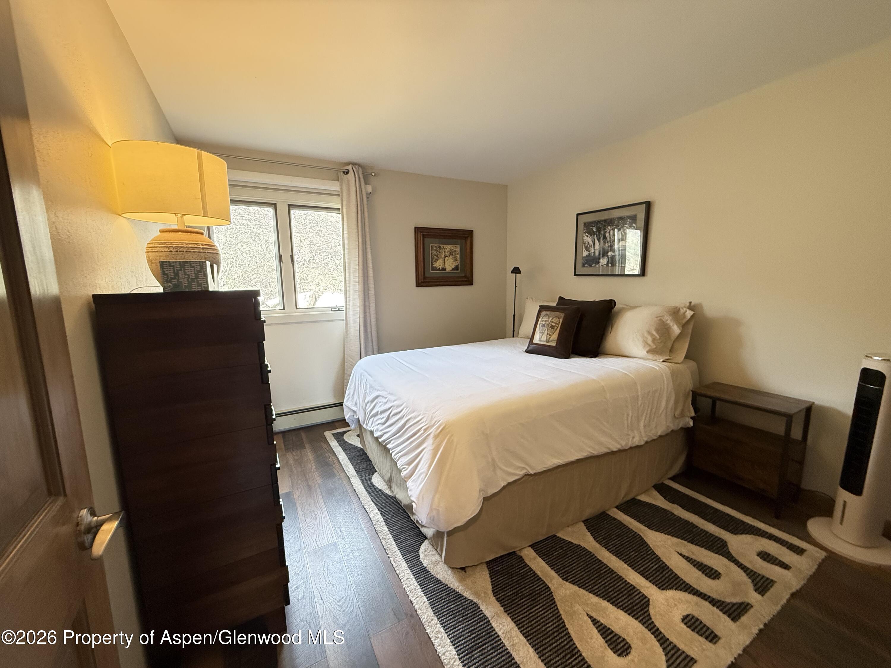 55 Upper Woodbridge Road, Unit E2 Snowmass Village, CO 81615 - Photo 9 of 41 a bedroom with a bed and wooden floor