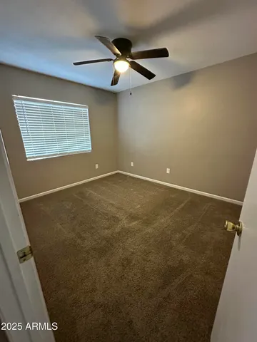 an empty room with a ceiling fan and a window