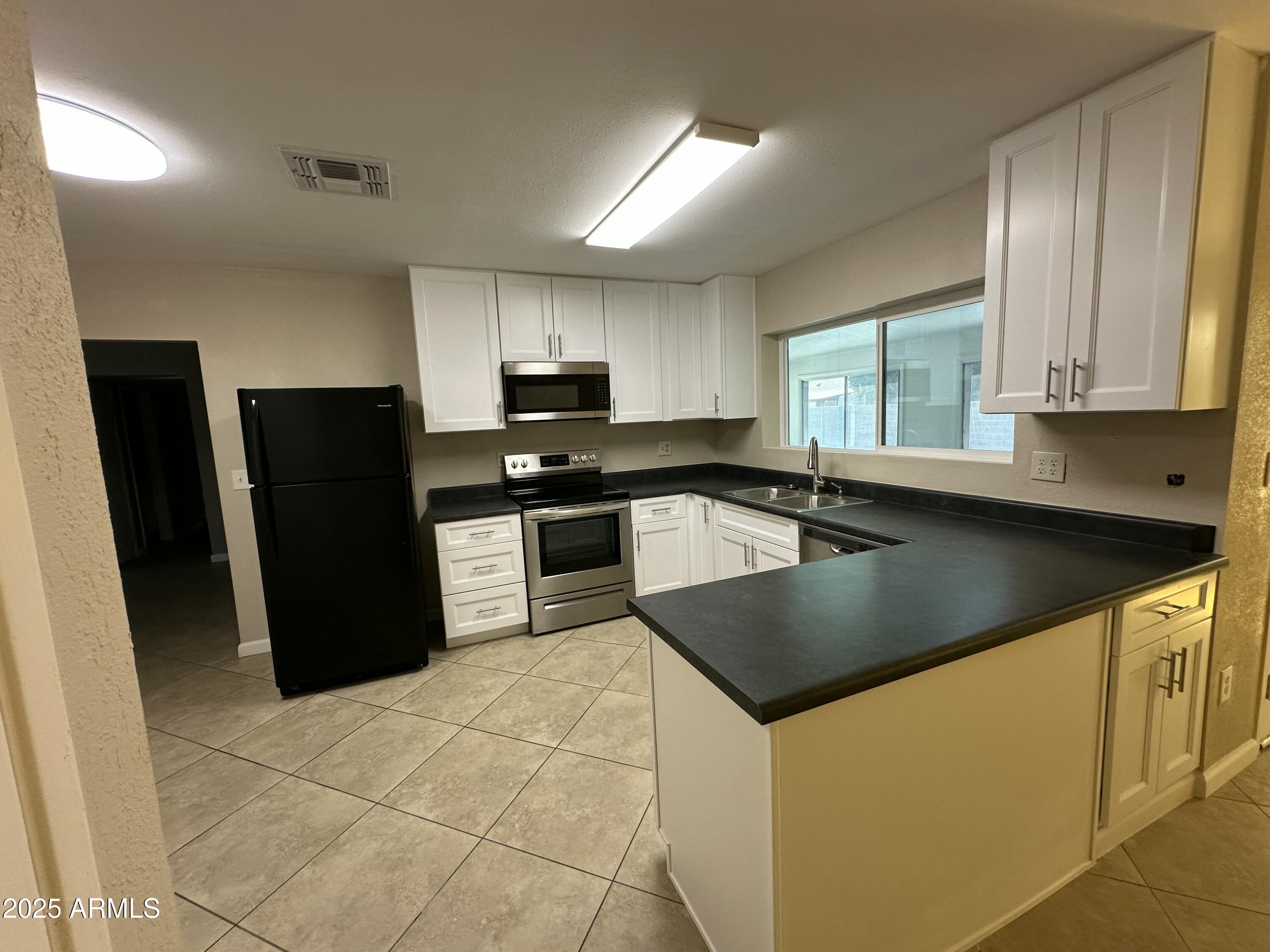 4639 West Ruth Avenue Glendale, AZ 85302 - Photo 4 of 23 a kitchen with stainless steel appliances granite countertop a sink a stove a refrigerator a sink a counter top space and cabinets