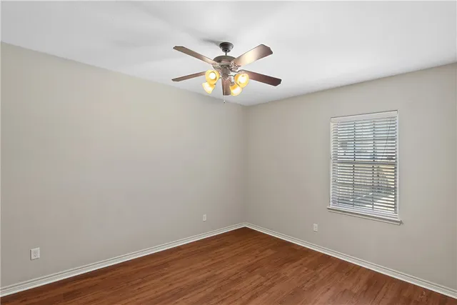 a view of an empty room with window and wooden floor