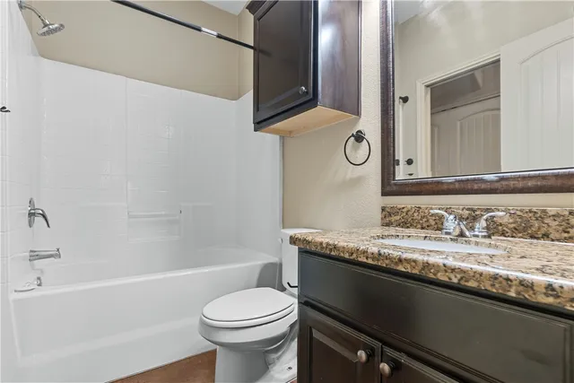 a bathroom with a granite countertop bathtub sink vanity mirror and toilet