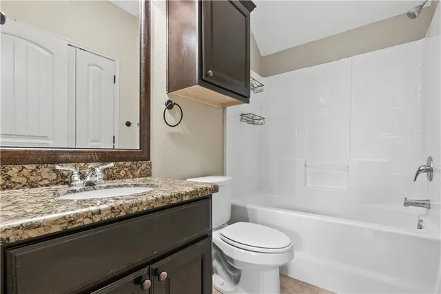 a bathroom with a granite countertop sink toilet and mirror