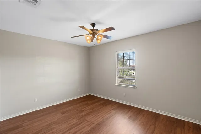 a view of an empty room with window and wooden floor