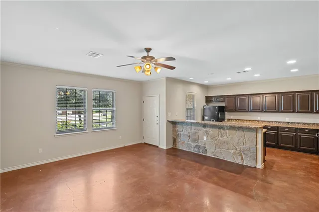 a view of kitchen with stainless steel appliances granite countertop a stove a sink a refrigerator and a dining table with wooden floor
