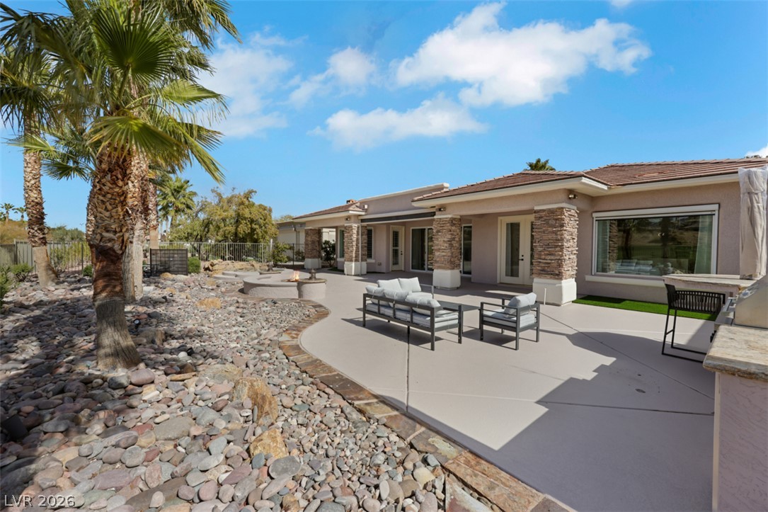 5015 Rivedro Street Las Vegas, NV 89135 - Photo 66 of 91 An inviting outdoor living space features a fire pit, spacious patio, and desert landscaping with palm trees.