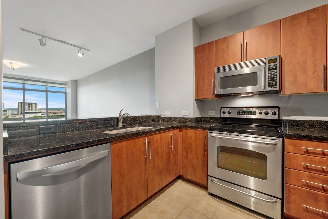 54 Rainey Street, Unit 810 Austin, TX 78701 - Photo 10 of 35 a kitchen with stainless steel appliances granite countertop a stove microwave and sink