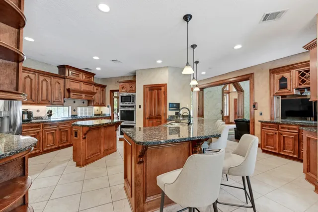 a kitchen with stainless steel appliances kitchen island granite countertop a table chairs and a refrigerator