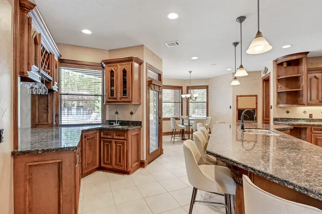 a kitchen with stainless steel appliances granite countertop a stove top oven a sink dishwasher a dining table and chairs with wooden floor