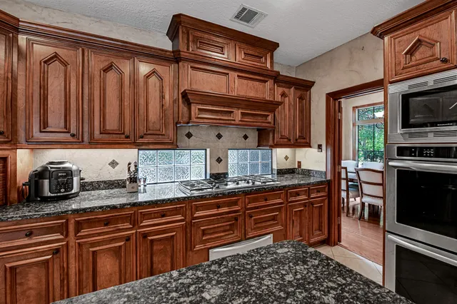 a kitchen with stainless steel appliances granite countertop a stove a sink and a microwave