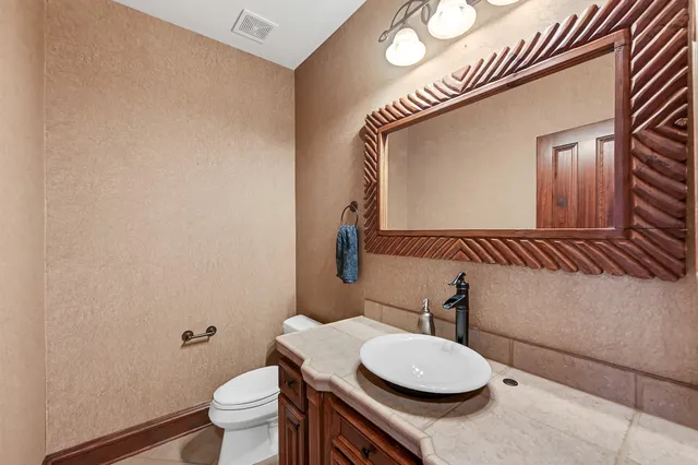 a bathroom with a granite countertop toilet sink and mirror