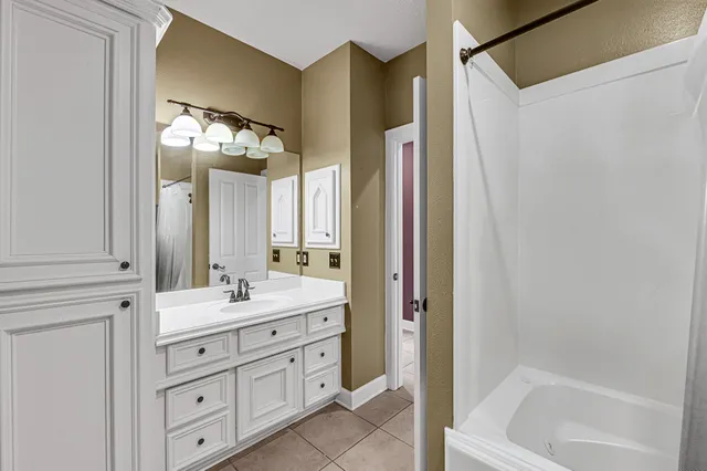 a bathroom with a double vanity sink mirror and bathtub