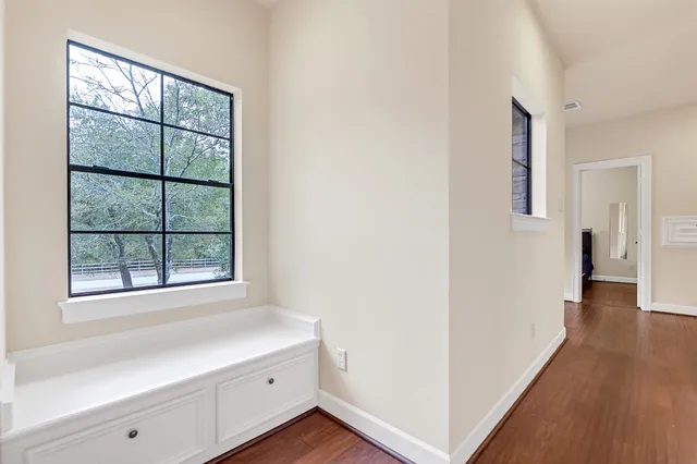 a view of a hallway to a livingroom with wooden floor and a window