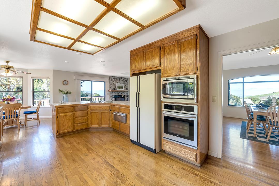 3130 Springview Lane San Jose, CA 95140 - Photo 9 of 47 a kitchen with stainless steel appliances kitchen island granite countertop a refrigerator a stove a dining table and chairs with wooden floor