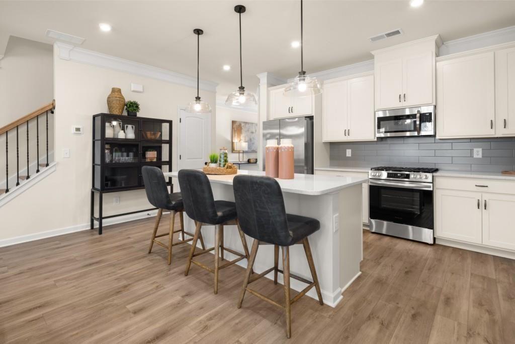120 Andros Drive, Unit 22A Dalton, GA 30721 - Photo 6 of 43 a kitchen with stainless steel appliances granite countertop a stove a refrigerator a kitchen island a dining table and chairs with wooden floor