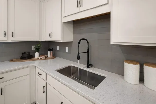 a kitchen with white cabinets a sink and dishwasher