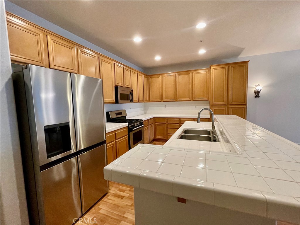 26 Cabazon Irvine, CA 92602 - Photo 3 of 9 a kitchen with stainless steel appliances granite countertop a refrigerator a sink a stove and a refrigerator with wooden floor