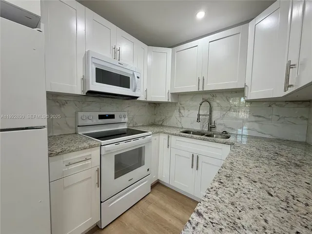 a kitchen with white cabinets stainless steel appliances and sink