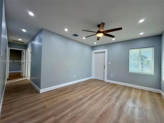an empty room with wooden floor and a ceiling fan