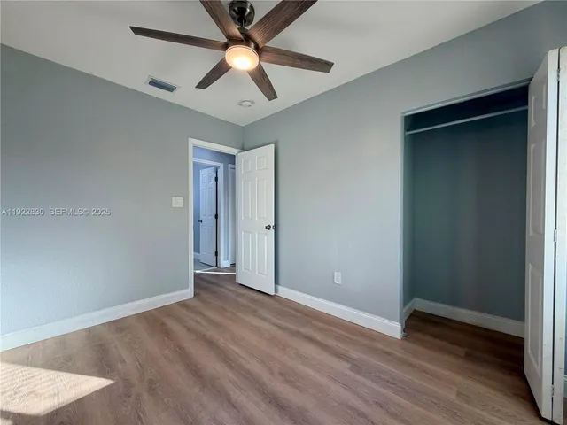 an empty room with wooden floor and a ceiling fan