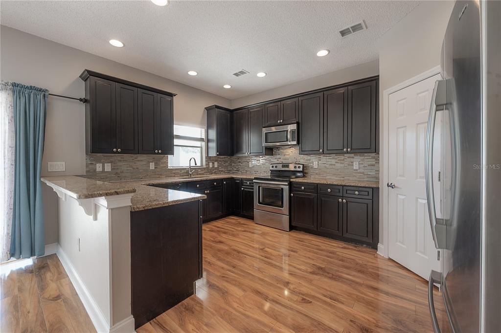 2012 Fern Ridge Court Holiday, FL 34691 - Photo 13 of 54 a kitchen with stainless steel appliances granite countertop a refrigerator sink and cabinets