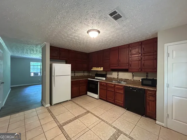 a kitchen with granite countertop a refrigerator and a stove top oven